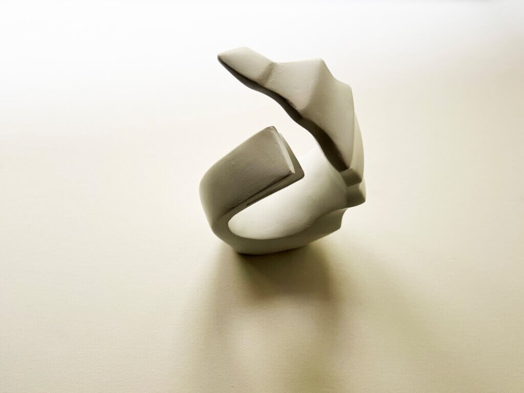 Curved white ceramic sculpture symbolizing unity and flow, reflecting themes of migration, belonging, and shared humanity.